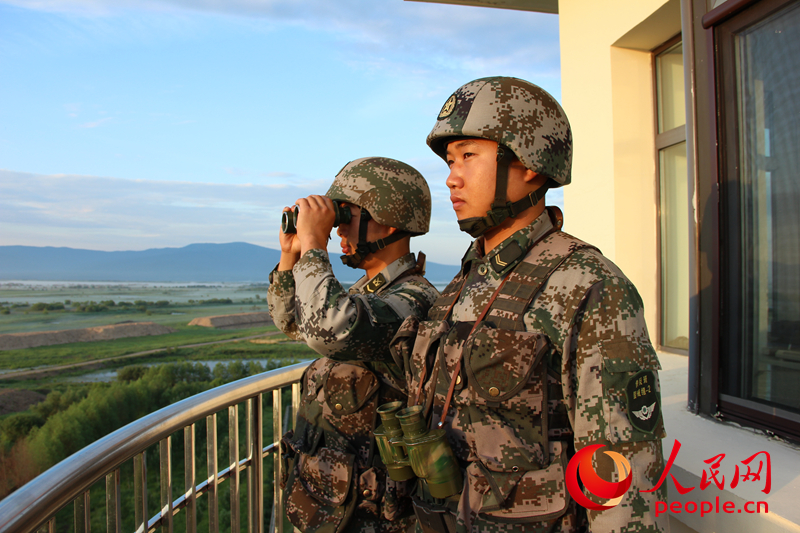 哨兵沈建前和董宇在东极哨所上观察陆界和江界，远处山脚下的薄雾还没有完全散去。（人民网记者 曹昆 摄）